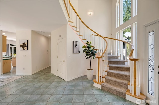 stairs with baseboards, tile patterned flooring, and a towering ceiling
