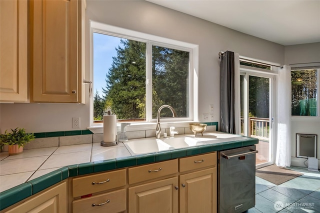 kitchen featuring tile countertops, dishwasher, a sink, and plenty of natural light