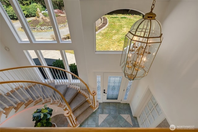 tiled foyer featuring an inviting chandelier, a towering ceiling, and stairway
