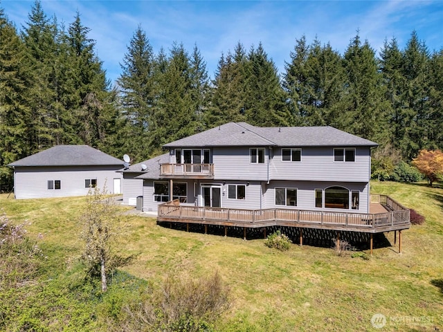 rear view of property featuring a yard, a deck, and a balcony