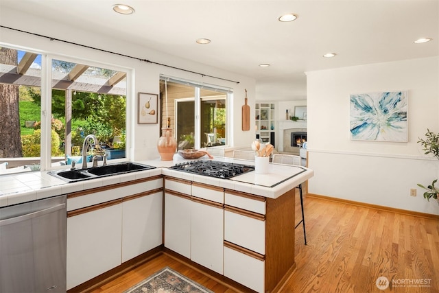 kitchen featuring white cabinets, plenty of natural light, dishwasher, and a sink