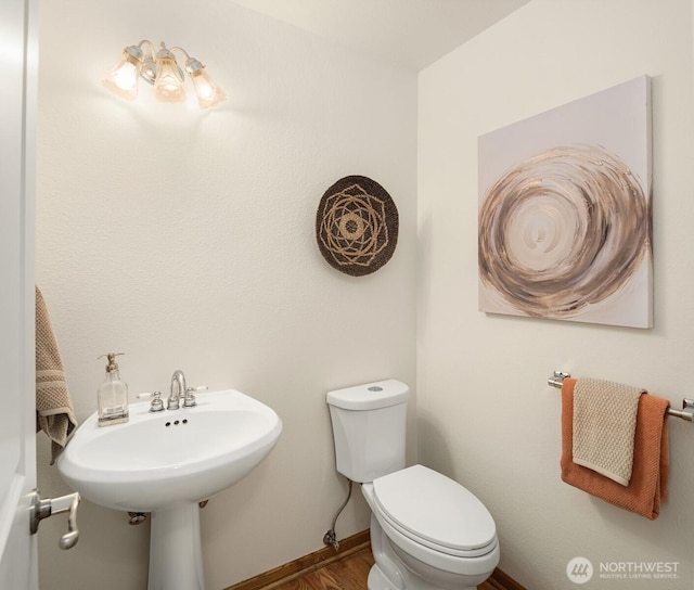 bathroom featuring toilet, wood finished floors, and baseboards