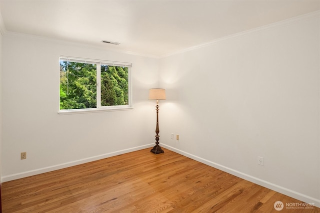 spare room with light wood-style floors, crown molding, baseboards, and visible vents