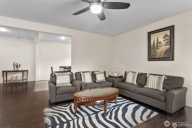 living area with baseboards, a ceiling fan, and wood finished floors