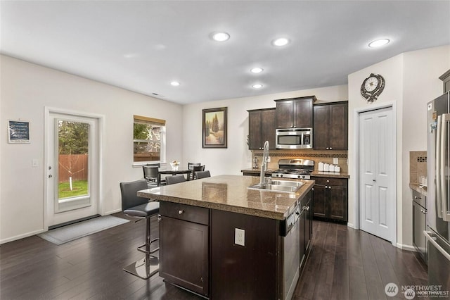 kitchen featuring appliances with stainless steel finishes, a sink, dark wood-type flooring, and a breakfast bar area