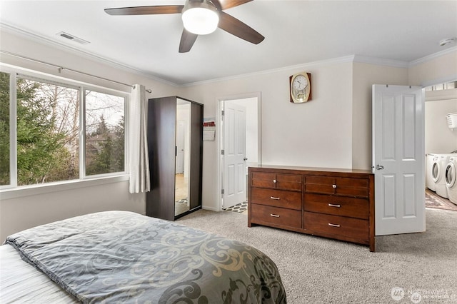 bedroom with visible vents, light colored carpet, a ceiling fan, washer and dryer, and ornamental molding