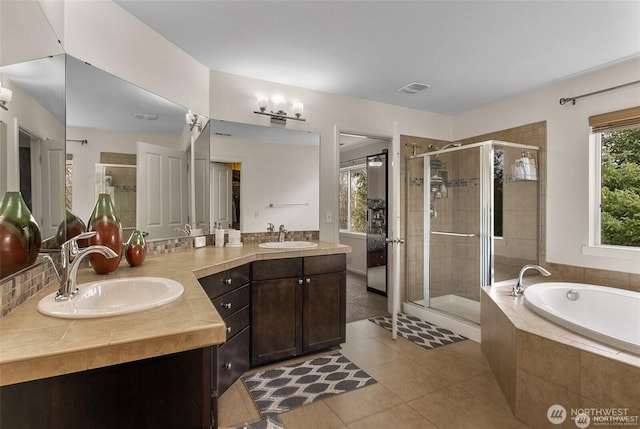 bathroom featuring tile patterned floors, a sink, double vanity, a stall shower, and a garden tub
