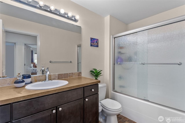 ensuite bathroom with ensuite bath, vanity, bath / shower combo with glass door, and toilet