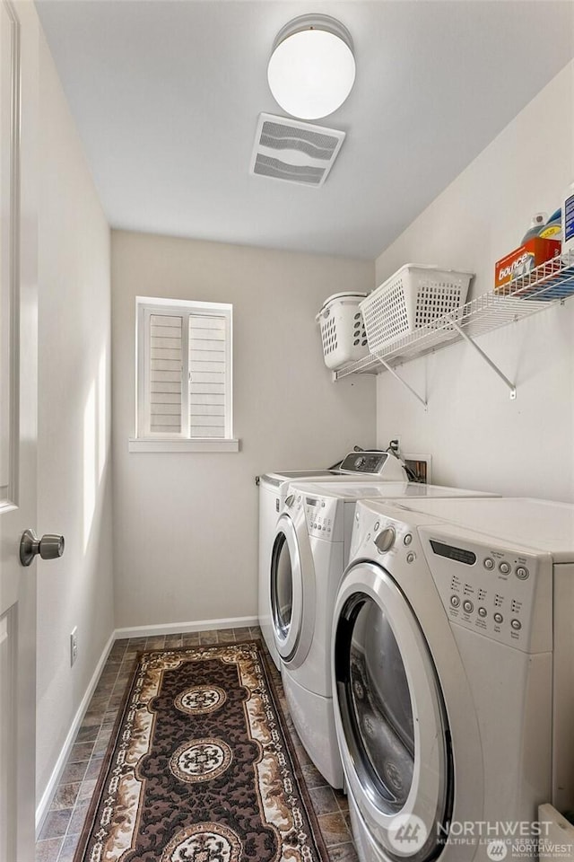 clothes washing area with washing machine and dryer, baseboards, laundry area, and visible vents
