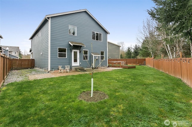 back of house with a fenced backyard, entry steps, and a yard