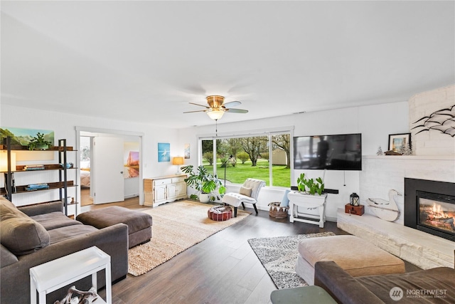 living room with wood finished floors, a fireplace, and a ceiling fan