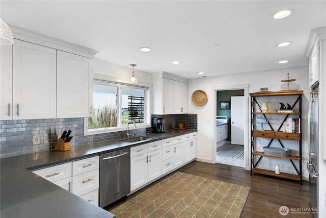 kitchen with tasteful backsplash, dark countertops, dark wood-type flooring, dishwasher, and a sink