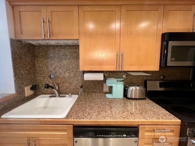 326 Queen Anne Ave N Unit 502, Seattle, WA 98109 - kitchen with light countertops, appliances with stainless steel finishes, decorative backsplash, and a sink