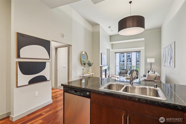 kitchen featuring a sink, dishwasher, tile counters, open floor plan, and dark wood-type flooring