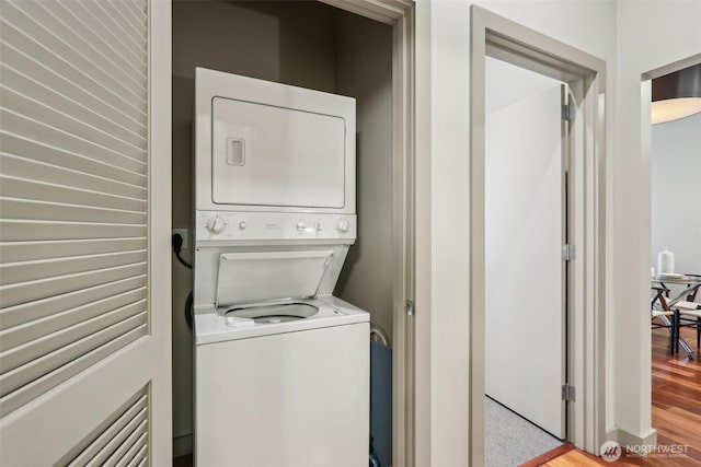 washroom featuring laundry area, stacked washer / dryer, and wood finished floors