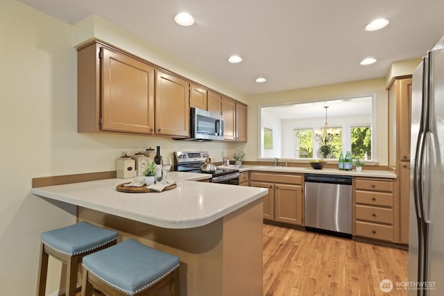 2003 Mill Pointe Dr SE, Mill Creek, WA 98012 - kitchen featuring stainless steel appliances, a peninsula, light wood finished floors, light countertops, and recessed lighting