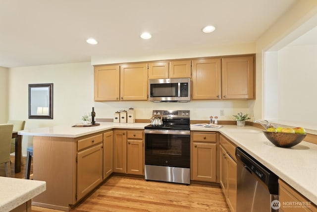 2003 Mill Pointe Dr SE, Mill Creek, WA 98012 - kitchen featuring stainless steel appliances, a peninsula, light countertops, a sink, and light wood finished floors