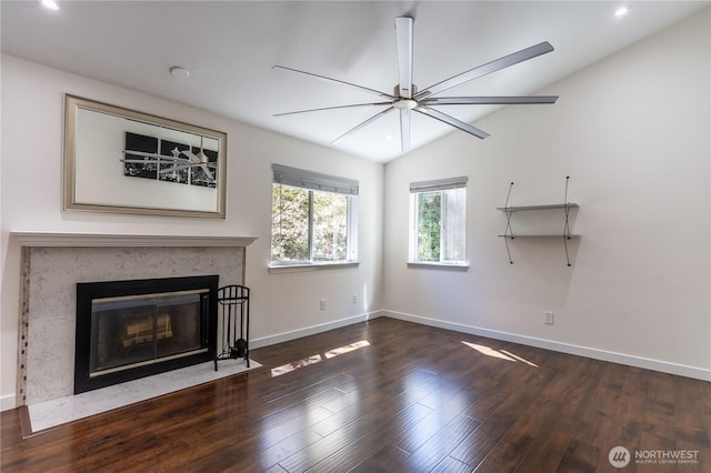 unfurnished living room featuring vaulted ceiling, wood finished floors, a high end fireplace, and baseboards
