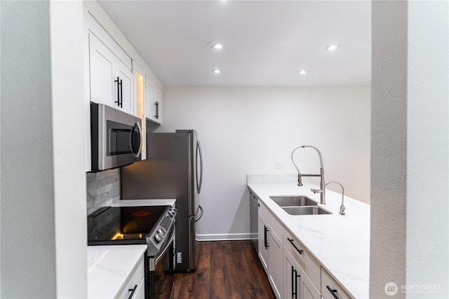 kitchen with recessed lighting, light stone countertops, a sink, appliances with stainless steel finishes, and dark wood finished floors