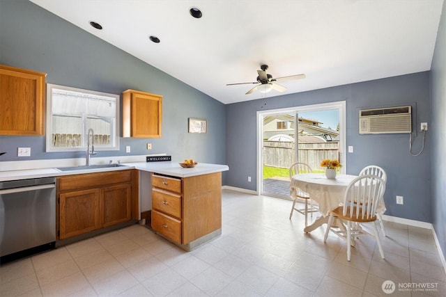 kitchen featuring a sink, a peninsula, a wall unit AC, stainless steel dishwasher, and lofted ceiling