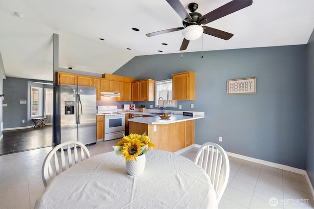 kitchen featuring white electric range oven, stainless steel fridge with ice dispenser, vaulted ceiling, under cabinet range hood, and light countertops