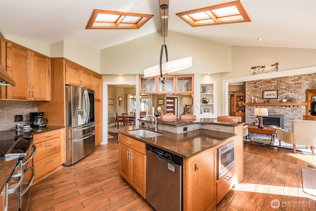 6250 Woodcock Rd, Sequim, WA 98382 - kitchen with appliances with stainless steel finishes, open floor plan, light wood-type flooring, a brick fireplace, and beam ceiling