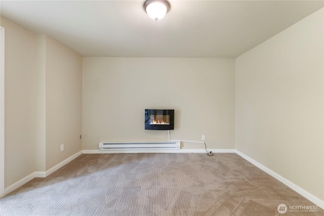 carpeted spare room featuring baseboards, a glass covered fireplace, and baseboard heating