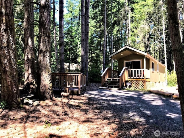 view of front of house featuring a view of trees, a wooden deck, and crawl space