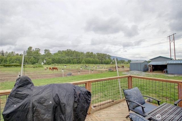wooden terrace with a rural view, a yard, and an outdoor structure