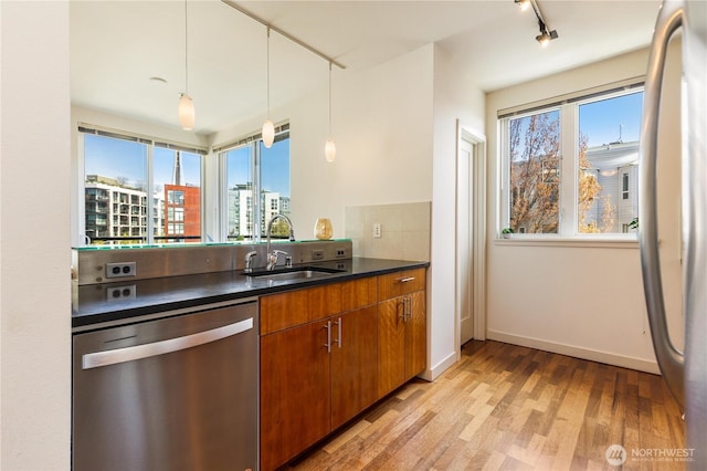3104 Western Ave Unit 603, Seattle, WA 98121 - kitchen featuring track lighting, a sink, dark countertops, stainless steel appliances, and light wood-style flooring