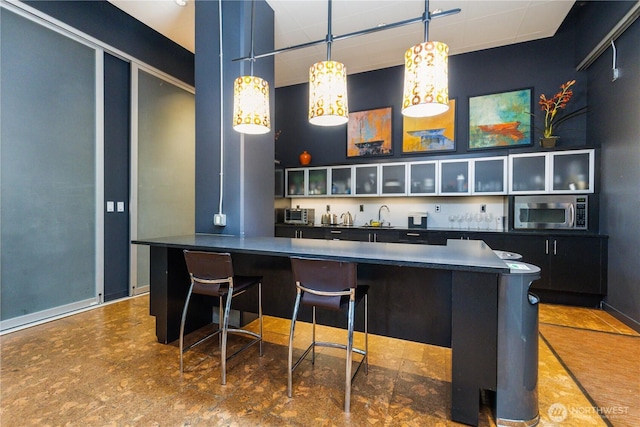 3104 Western Ave Unit 603, Seattle, WA 98121 - bar featuring hanging light fixtures, baseboards, a sink, a community bar, and stainless steel microwave