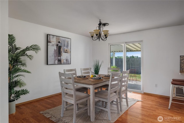 dining room with an inviting chandelier, light wood-style flooring, and baseboards