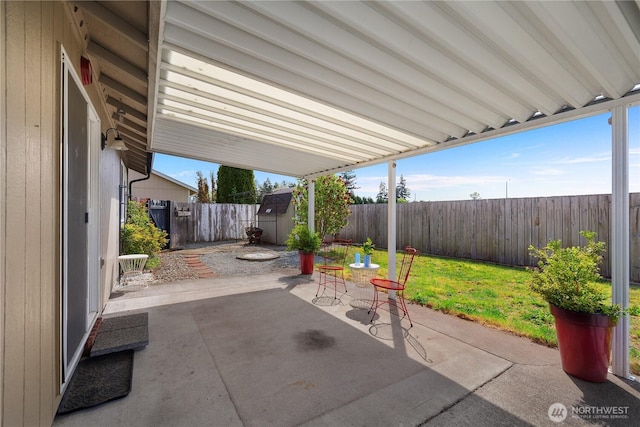 view of patio / terrace featuring a fenced backyard, a storage unit, and an outbuilding