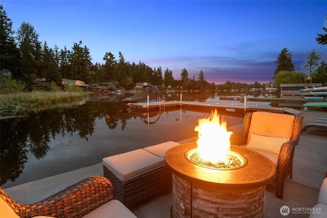 patio terrace at dusk featuring an outdoor fire pit and a water view