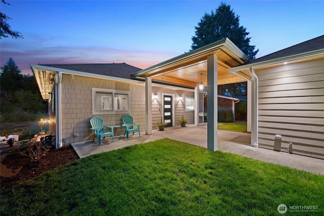 rear view of property featuring a patio, a lawn, and roof with shingles