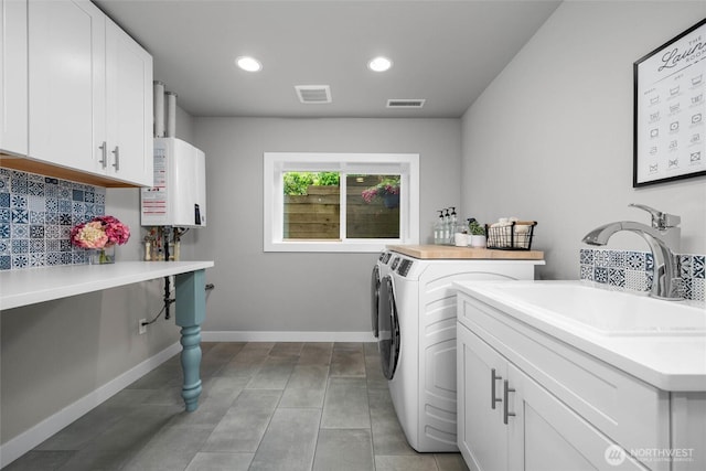 laundry area featuring tankless water heater, washing machine and dryer, recessed lighting, baseboards, and tile patterned floors