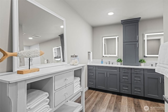 full bath featuring wood finished floors, double vanity, and recessed lighting