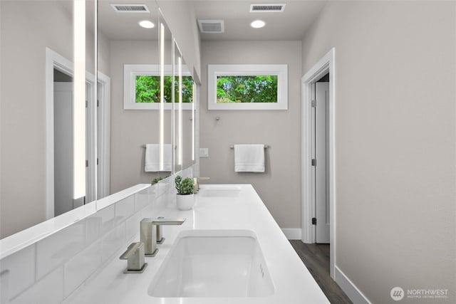 full bath with baseboards, wood finished floors, and double vanity