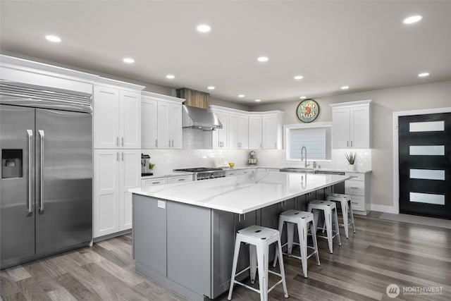 kitchen featuring appliances with stainless steel finishes, a large island, white cabinets, tasteful backsplash, and wood finished floors