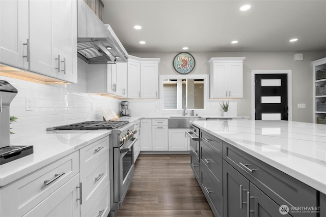 kitchen featuring stainless steel appliances, recessed lighting, white cabinetry, gray cabinets, and wall chimney exhaust hood