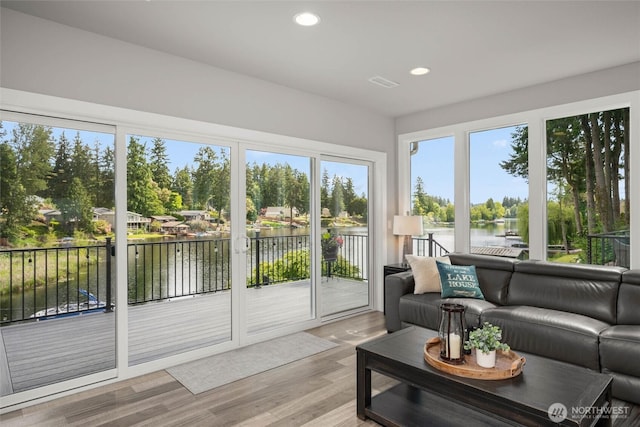 sunroom / solarium with recessed lighting, wood finished floors, and a deck with water view