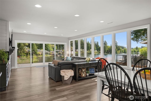 sunroom / solarium with a water view, recessed lighting, and wood finished floors