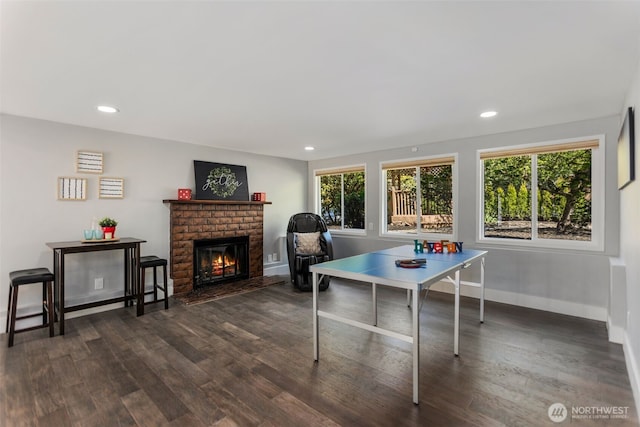 playroom with recessed lighting, dark wood finished floors, a brick fireplace, and baseboards