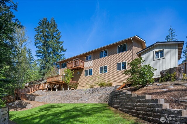 rear view of property with a lawn, a balcony, a deck, and stairs