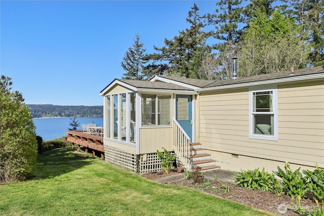 view of front of home featuring crawl space, a water view, entry steps, a front yard, and a sunroom