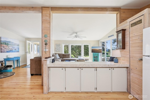 kitchen featuring lofted ceiling with beams, open floor plan, light wood finished floors, light countertops, and white cabinetry