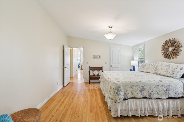 bedroom featuring lofted ceiling, baseboards, and light wood-style floors