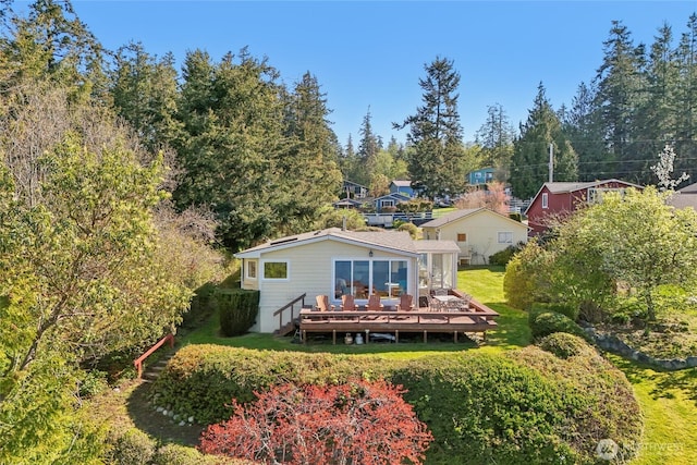 back of property featuring a wooden deck and a yard