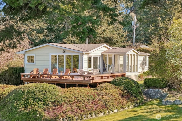 rear view of property featuring a wooden deck and a sunroom