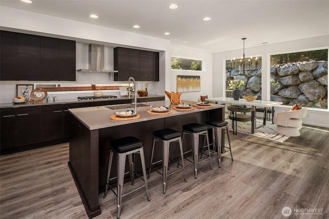 16515 26th St E, Lake Tapps, WA 98391 - kitchen with modern cabinets, a sink, wall chimney range hood, a kitchen bar, and wood finished floors